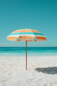 Sie sehen einen Sonnenschirm im Sand stehend vor türkisfarbenem Meer